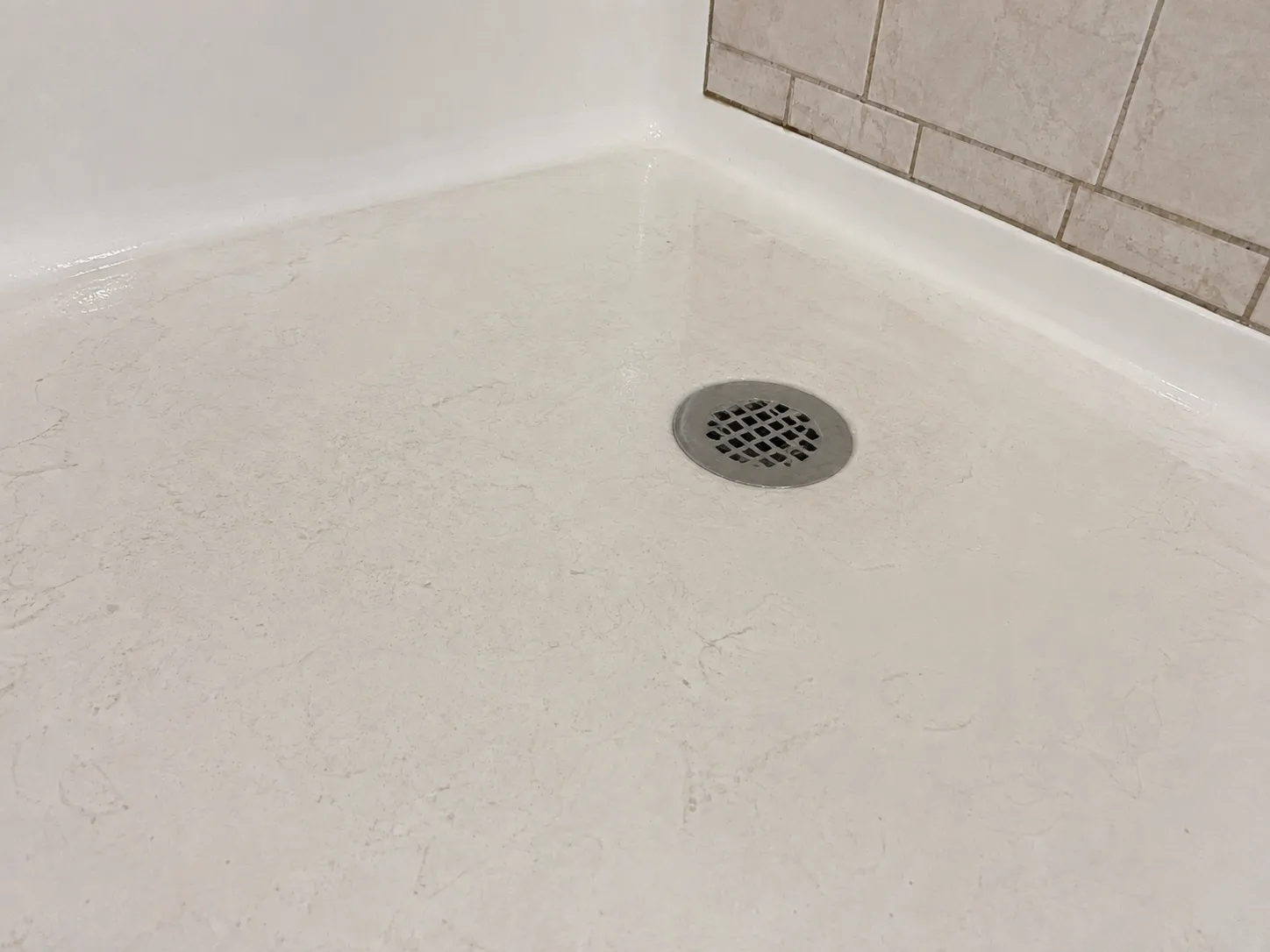 The same shower base after clearing — dry, with an open drain grate